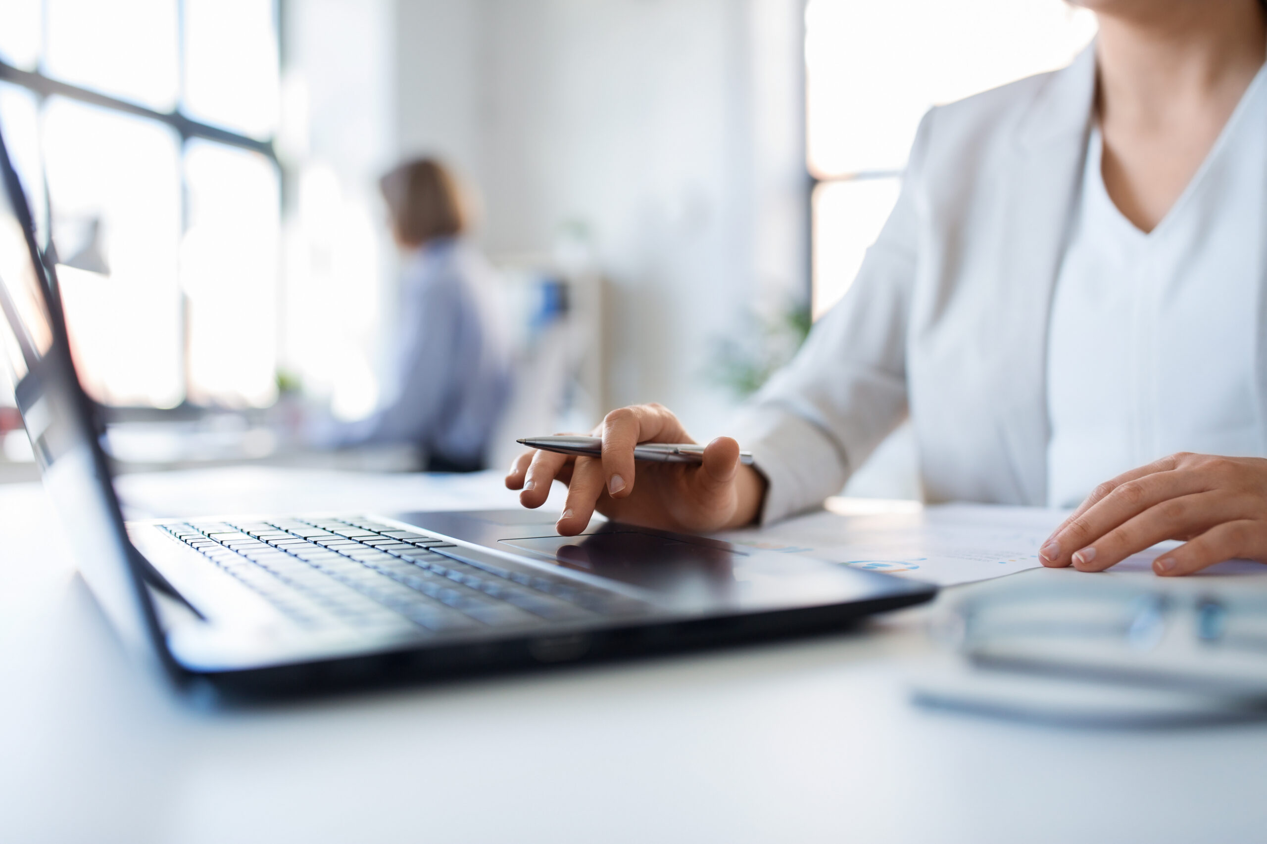 Frau arbeitet am Laptop mit einem Stift in der Hand